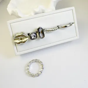 Detailed view of a silver-toned five-piece ring set with gems and a lip motif.