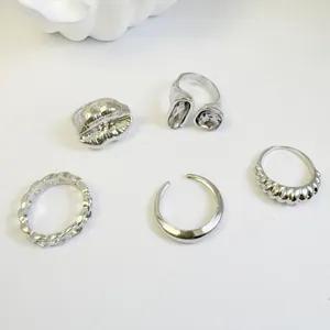 Close-up detail of five silver-toned rings featuring retro geometric and stone designs.