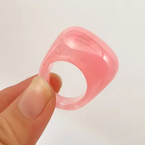Close-up of minimalist pink acrylic oval ring with transparent resin finish