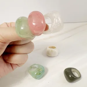 Macro view of colorful minimalist acrylic rings with marble texture on white surface
