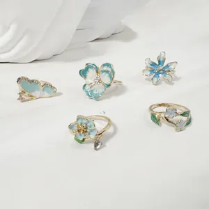 Juego de anillos de flores y mariposas de esmalte azul claro con detalles de strass.