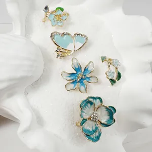 Detalle de un conjunto de anillos de flores y mariposas en esmalte azul y pedrería.