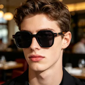 Professional close-up of stylish black square frame sunglasses worn by a male model in a cafe