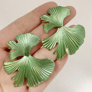 Gros plan de boucles d'oreilles ginkgo en métal vert avec texture détaillée