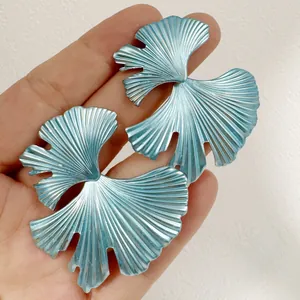 Vue détaillée de boucles d'oreilles bleu clair en forme de feuille de ginkgo texturée.