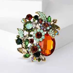 Close-up of a luxury floral brooch with colorful glass crystals and large orange stone.