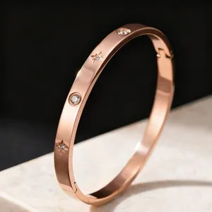 Détail d'un jonc en acier titane or rose avec étoile gravée et pierres en oxyde de zirconium