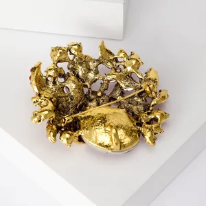 Detailed back view of a luxury gold-tone brooch showing the secure pin and hammered texture