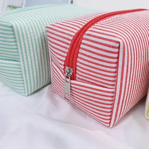 Close-up detail of a red and white striped seersucker cosmetic bag with durable metal zipper