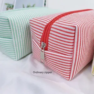 Close-up detail of a red and white striped seersucker cosmetic bag with durable metal zipper