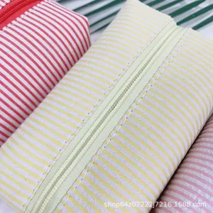 Close-up detail of seersucker cosmetic bag with yellow and white stripes and zipper closure