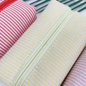Close-up detail of seersucker cosmetic bag with yellow and white stripes and zipper closure