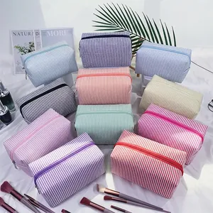 Detailed view of colorful striped seersucker cosmetic bags and pouches arranged together.