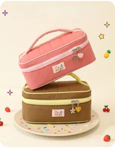 Detailed view of two macaron-colored travel makeup bags in pink and brown with cute charms