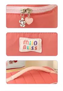 Close-up of pink cosmetic bag details including heart zipper and soft padded handle