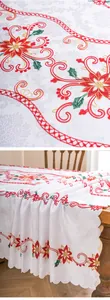 Close-up of elegant red floral embroidery and lace edge on a white tablecloth.