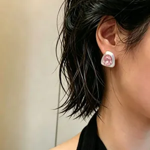 Detailaufnahme von Ohrsteckern mit rosa Zirkon und unregelmäßigem weißem Rahmen