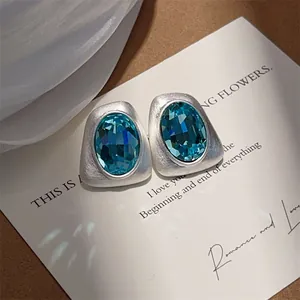 Detailansicht von unregelmäßigen gebürsteten Ohrsteckern mit ovalen blauen Zirkonia