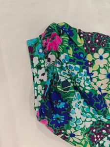 Close-up detail shot of the vibrant green floral print puff sleeve on a women's dress