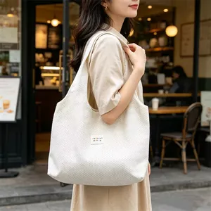 Model carrying a large capacity white polka dot tote bag in a casual street setting.