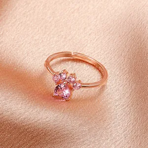Close-up of rose gold cat paw ring with pink heart-shaped gemstones on satin background