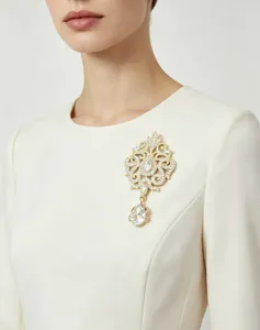 Detail view of a vintage crystal brooch with teardrop pendant pinned to a white neckline