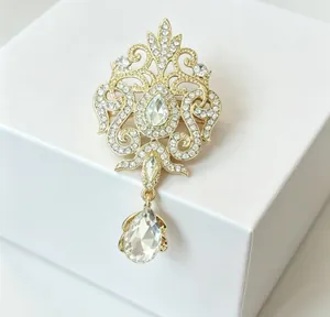 Close-up of vintage gold water-drop crystal brooch on a white jewelry gift box.