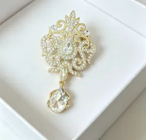 Detail view of a vintage gold-tone crystal brooch with a teardrop pendant in a gift box