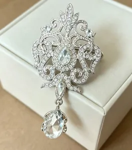 Close-up view of vintage silver crystal brooch with pear-shaped water drop pendant detail.