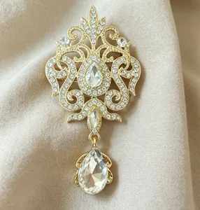 Detail of vintage gold brooch featuring shimmering crystals and large teardrop pendant.