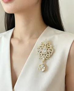 Close-up of a luxury vintage gold crystal brooch with teardrop pendant on white dress