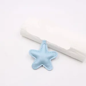 Close-up detail of a light blue padded faux leather star pendant with white stitching.