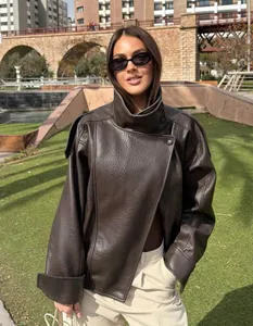 Detail view of a vintage dark brown litchi grain leather jacket on a model outdoors.