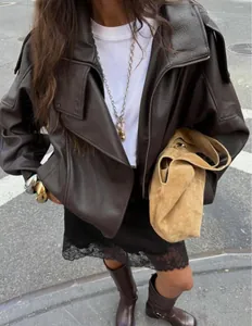 Detail view of a vintage brown lychee grain leather jacket in a stylish street outfit.