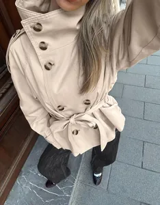 Detailed view of a stylish beige short trench coat featuring a high collar and waist tie belt.