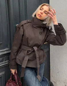 Detailed view of women's short brown trench coat featuring double-breasted buttons and belt