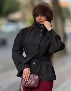 Detail view showing the elegant black double-breasted short trench coat with a waist belt.