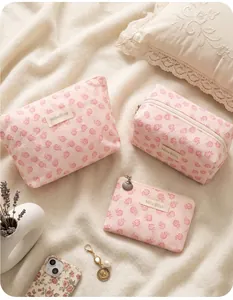 Set of pink jacquard floral lace makeup bags on soft beige bedding with lifestyle props