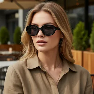 Stylish black oval sunglasses worn by a blonde model in a sunny outdoor cafe setting