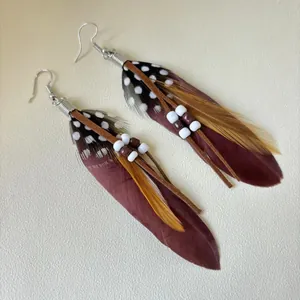 Detailed view of bohemian long fringe earrings with brown and spotted feathers