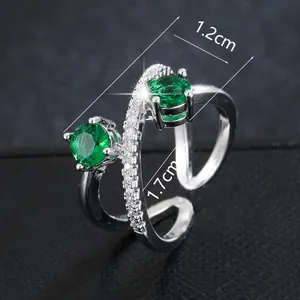 Detail view of cross-winding silver ring with round green gemstones