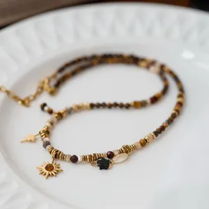 Close-up of bohemian beaded necklace with sun and star pendants on a white plate