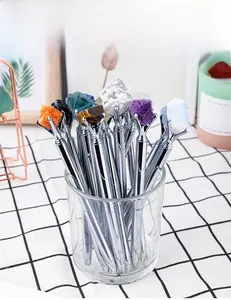 Detail of silver metal ballpoint pens topped with natural raw crystal stones