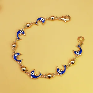 Detail of ocean-style gold bracelet with blue dolphin charms and evil eye pattern
