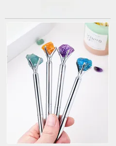 Close-up of creative silver metal ballpoint pens featuring colorful natural raw crystal stones