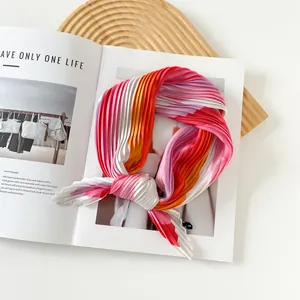 Detail of a vibrant pleated satin scarf with colorful prints displayed on a magazine
