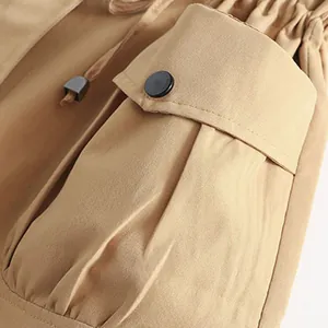 Close-up detail of khaki vest featuring a flap pocket with button and drawstring