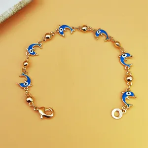 Close-up of bohemian golden chain bracelet featuring blue dolphin evil eye charms.