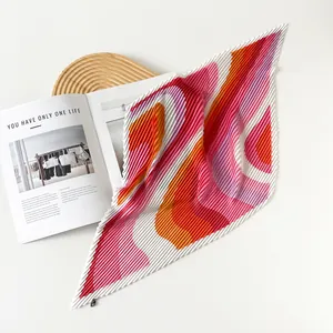 Detail shot of a colorful pleated satin square scarf with artistic wavy print patterns