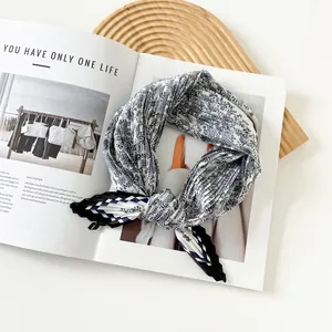 Close-up detail of blue paisley pleated silk scarf with checkered border on magazine